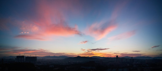 Hermoso panorama natural puesta de sol amanecer sobre siluetas horizonte de la ciudad y asombroso cielo azul nube naranja sobre él