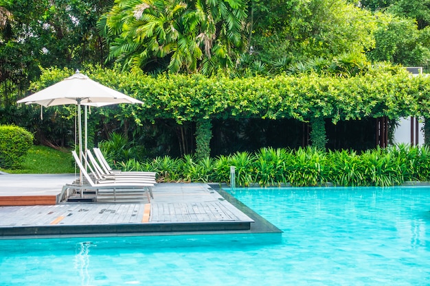 Hermoso paraguas de lujo y una silla alrededor de la piscina en el hotel y resort