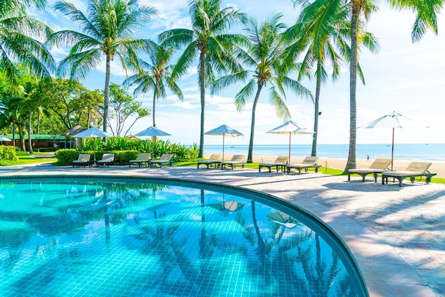 Hermoso paraguas y silla alrededor de la piscina en el hotel y resort