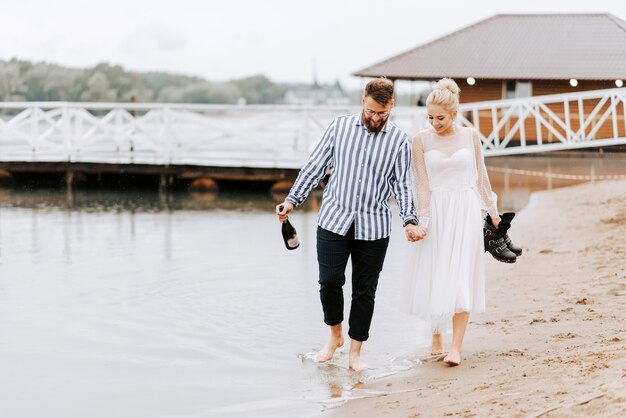 Hermoso paseo de recién casados por la costa descalzo y tomarse de las manos.