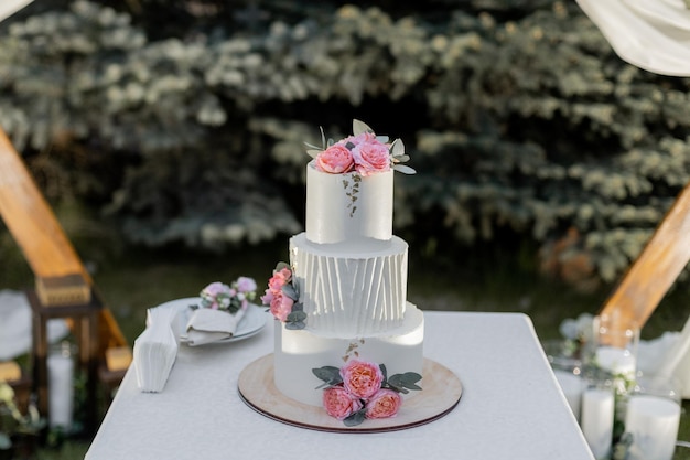 Foto hermoso pastel de boda cerca del arco de la boda por la noche