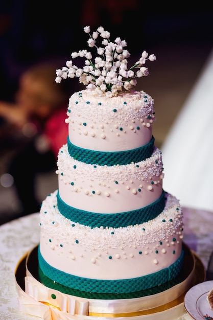 Hermoso pastel de bodas decorado con lirios del valle y abalorios