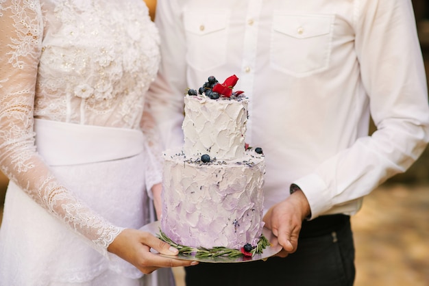 Hermoso pastel de bodas con flores en el fondo de los recién casados