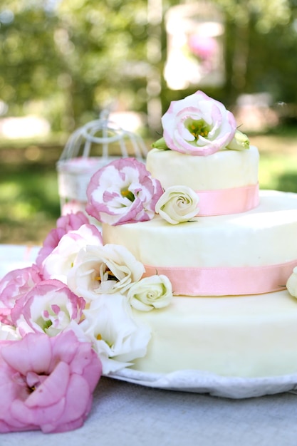 Hermoso pastel de bodas con flores en la mesa al aire libre