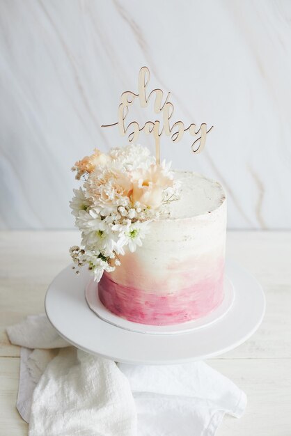 Foto hermoso pastel boho con una tapa y flores en una mesa blanca