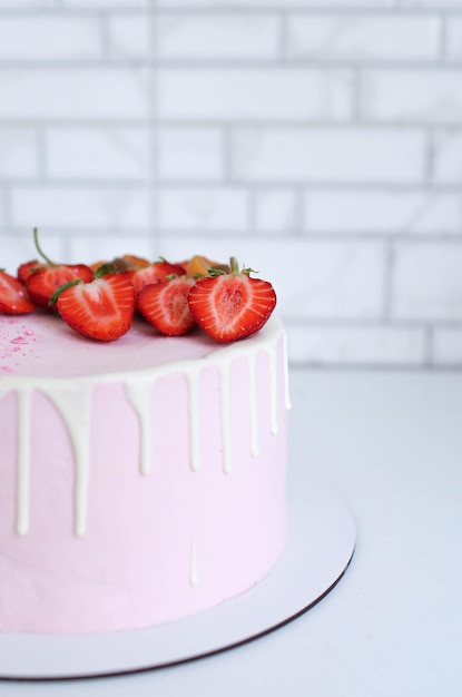 Foto hermoso pastel casero de color rosa pálido con fresas y albaricoque en un plato blanco cerrado