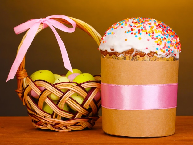 Hermoso pastel de Pascua con huevos en canasta sobre mesa de madera sobre fondo marrón