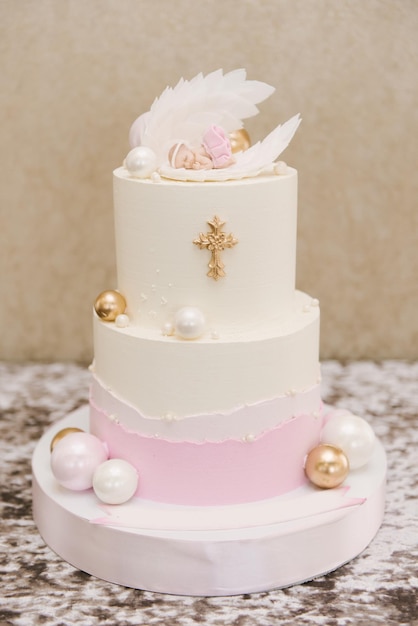 Un hermoso pastel rosa y blanco grande para un bebé para el bautismo