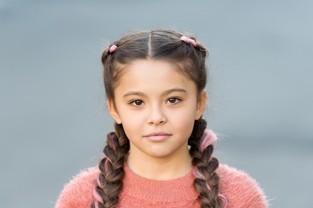 Hermoso peinado Peinado de moda para niños Niña pequeña con peinado de trenzas de moda Tendencia de moda Salón y cuidado del cabello Peinado de trenzas Chica con cara linda sonriendo al aire libre
