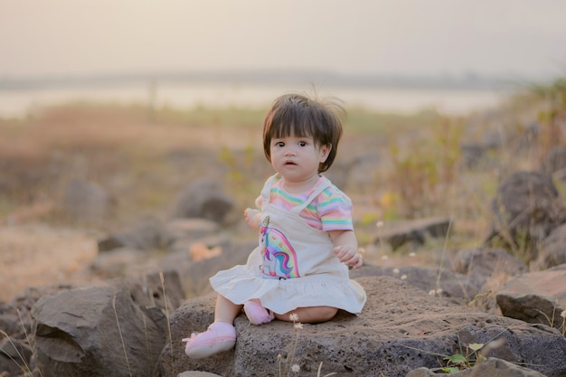 Foto hermoso pequeño bebé sentado en la roca.