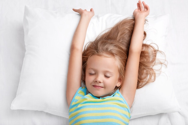 Hermoso pequeño niño adorable se estira en la cama