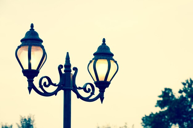 Hermoso poste de luz de estilo antiguo de la calle vintage con efecto de brillo desde la poca luz del atardecer