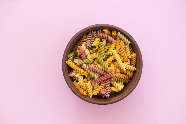 Hermoso primer plano de pasta farfalle de color crudo italiano sobre fondo rosa vista superior horizontal