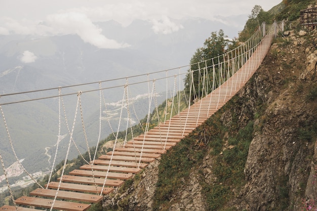 Hermoso puente colgante en las montañas, una fuerza emocionante de la naturaleza, edificios humanos entre los ...