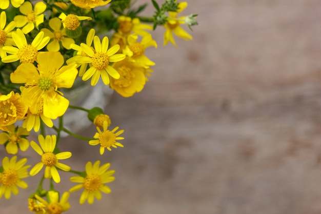 Hermoso ramo amarillo de flores se encuentra en un fondo de madera