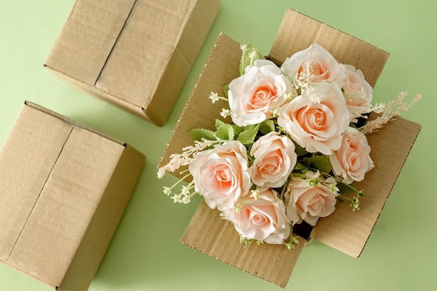 Un hermoso ramo floreciente de rosas rosadas en una caja de cartón de entrega de paquetes Concepto de vacaciones de regalo y servicio de logística