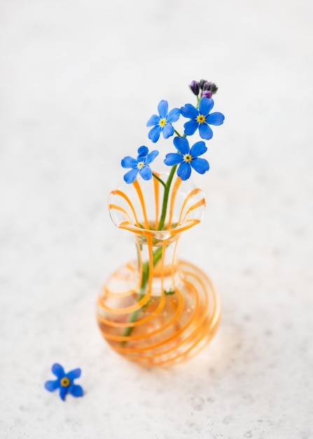 Hermoso ramo de flores azules no me olvides en un mini jarrón de vidrio naranja
