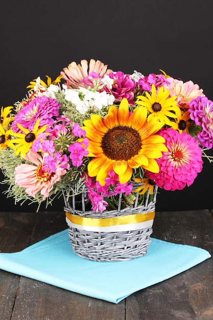 Hermoso ramo de flores brillantes en la mesa de madera sobre fondo negro