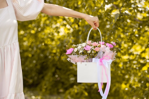 Un hermoso ramo de flores en una caja en manos de una hermosa chica sobre un fondo verde