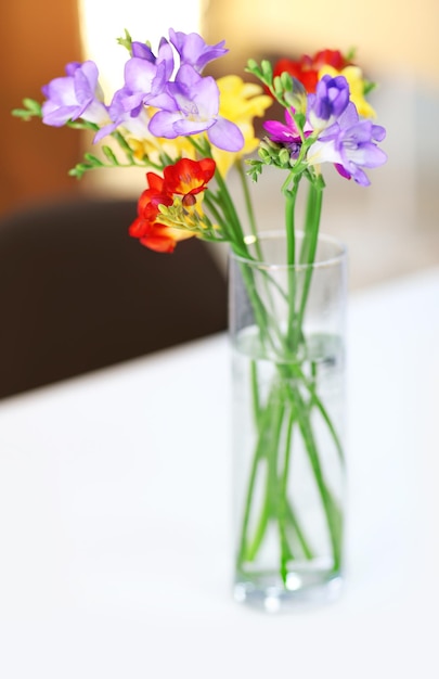 Hermoso ramo de flores de freesias coloridas en la mesa de madera en la sala de estar