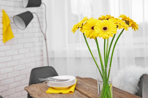 Hermoso ramo de flores de gerbera amarilla y utensilios en la mesa de madera