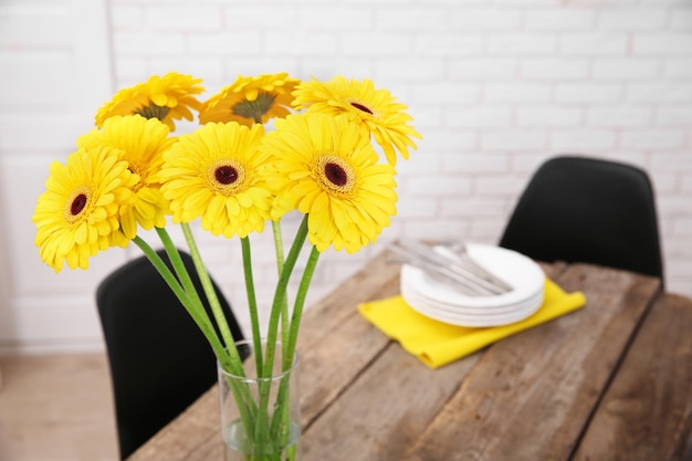 Hermoso ramo de flores de gerbera amarilla y utensilios en la mesa de madera