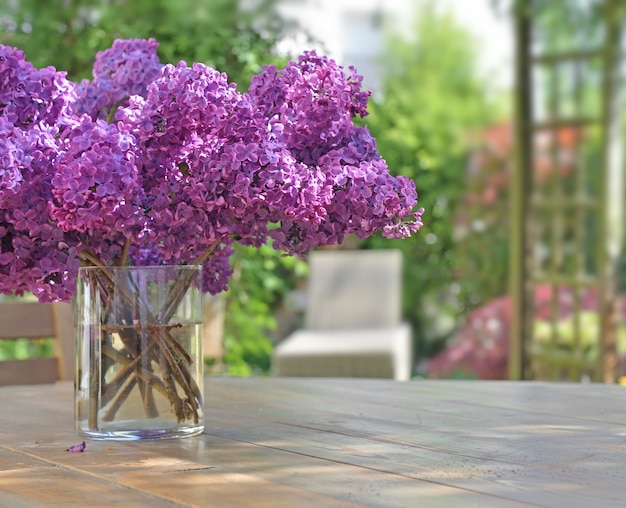 Hermoso ramo de flores lilas púrpura sobre una mesa de madera en el jardín