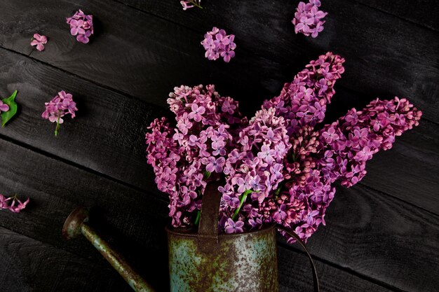 Hermoso ramo de flores lilas en regadera de metal