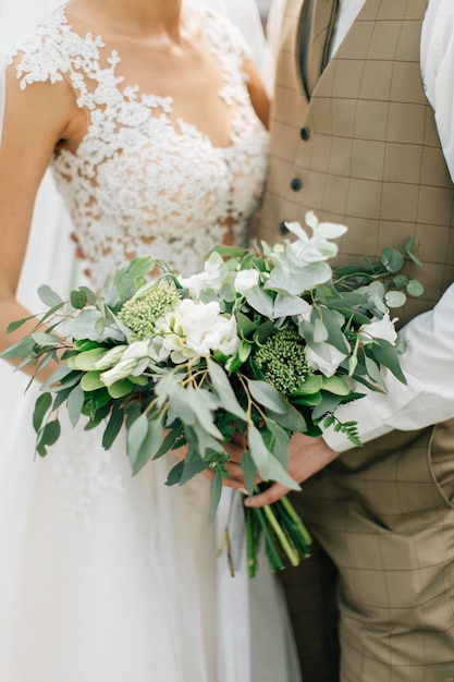 Hermoso ramo de flores en manos de la novia y el novio