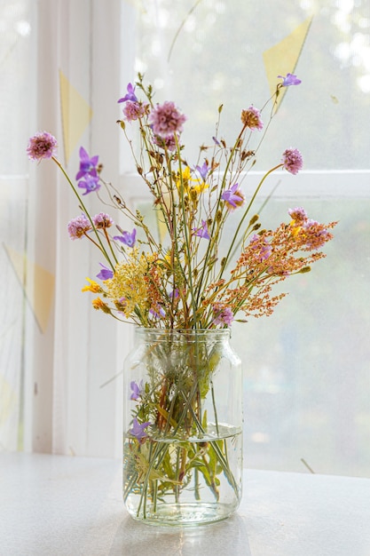 Hermoso ramo de flores silvestres con el telón de fondo de una ventana en una casa de madera