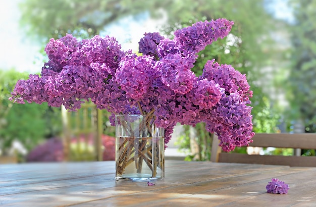 Hermoso ramo de lilas moradas sobre una mesa de madera en el jardín