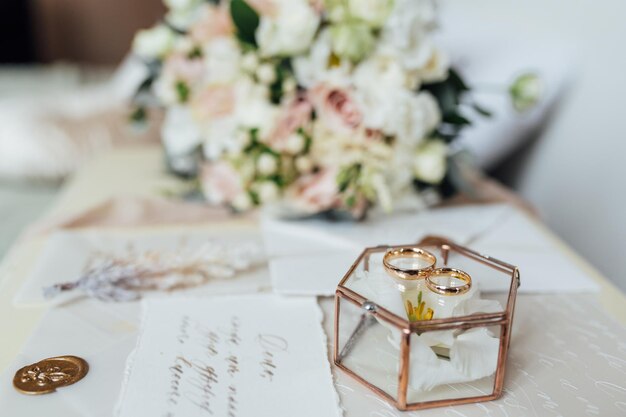 Hermoso ramo de novia y anillos de los recién casados cerca de las tarjetas de invitación estilo boho