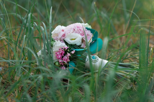 Hermoso ramo de novia de flores blancas y rosadas sobre la hierba verde.Elegante ramo de novia al aire libre