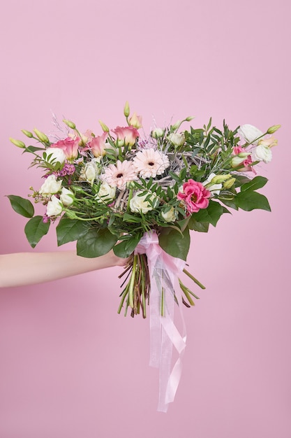 Hermoso ramo de novia en la mano sobre un fondo rosa. Flores delicadas