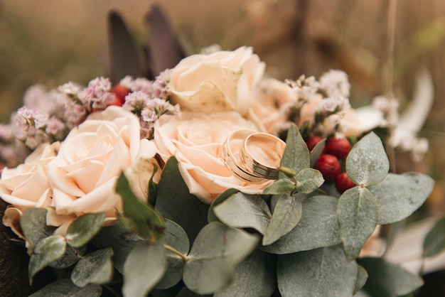 Hermoso ramo de novia con protea y anillos de boda de rosas sobre un fondo de bosque