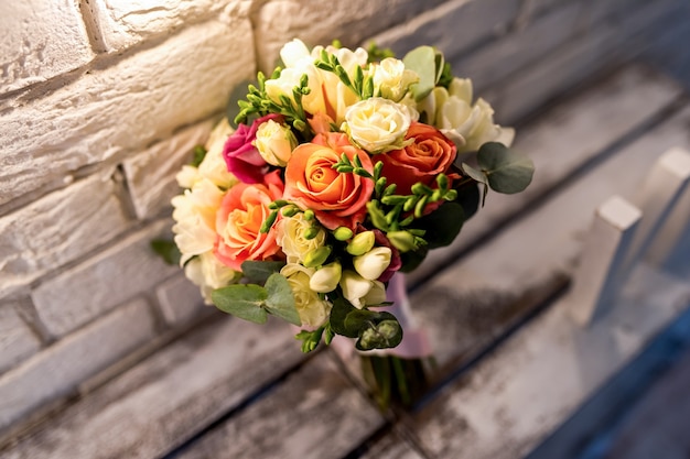 Hermoso ramo de novia. Rosas cerca de la pared de ladrillo blanco. Fondo vintage. Primer plano de accesorios de boda.