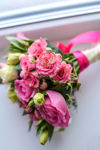 Hermoso ramo de novia de rosas rosadas con anillos de boda en él