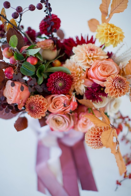 Hermoso ramo de otoño con flores y bayas naranjas y rojas Ramo de otoño con cintas sobre un fondo blanco