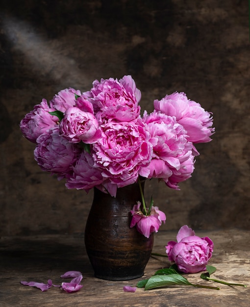 Hermoso ramo de peonías rosas en un jarrón sobre una mesa de madera