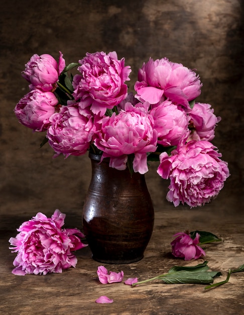 Hermoso ramo de peonías rosas en un jarrón sobre una mesa de madera