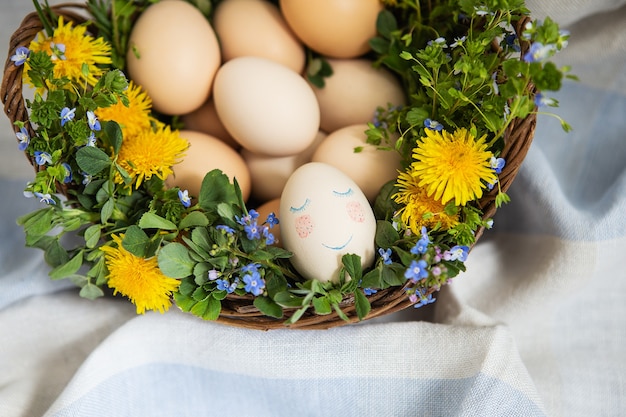 Foto hermoso ramo de primavera en una canasta de madera con huevos de pascua pintados, huevos con caras lindas