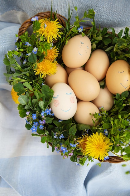 Hermoso ramo de primavera en una canasta de madera con huevos pintados de Pascua, huevos con caras lindas. Postal de Pascua.