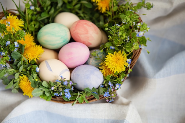 Un hermoso ramo primaveral en una canasta de madera con huevos de Pascua pintados con acuarelas