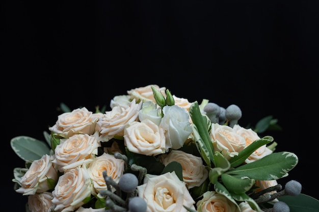 Hermoso ramo de rosas tupidas, eucaliptos, brunei, pittosporum y lisianthus en una pared negra.