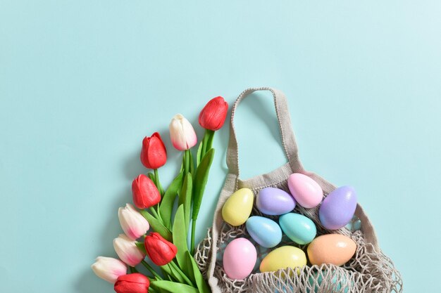 Un hermoso ramo de tulipanes con una bolsa de hilo que contiene huevos pintados Banner para las felices vacaciones de Pascua