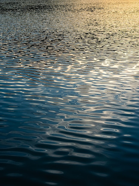 Hermoso Reflejó los rayos del sol que golpean la superficie del agua, el río es ondas en la superficie del mar antes del atardecer, el fondo natural