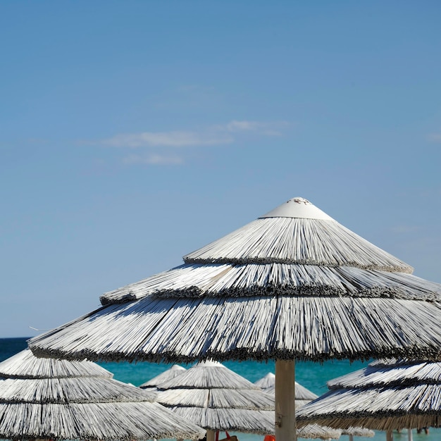 Hermoso resort de playa con sombrillas de paja blanca sobre un cielo azul y nubes blancas