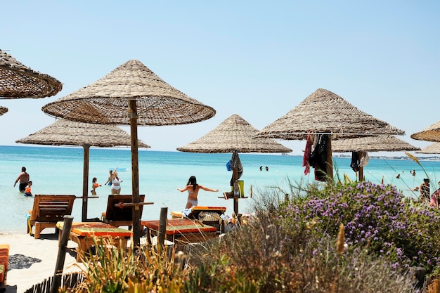 Hermoso resort de playa con sombrillas de paja en un cielo azul y nubes blancas