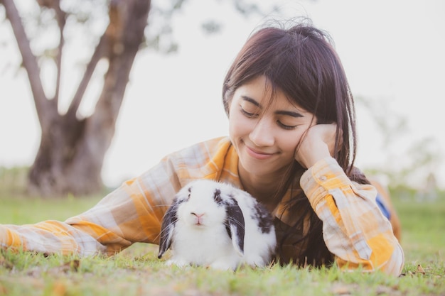 Hermoso retrato bonito de una joven mujer asiática con un lindo conejo en el concepto de cuidado de mascotas y animales mujer feliz sosteniendo un conejito en el campo al aire libre de la naturaleza con el concepto de Pascua de amistad