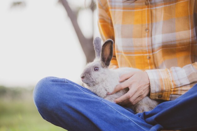 Foto hermoso retrato bonito de una joven mujer asiática con un lindo conejo en el concepto de cuidado de mascotas y animales mujer feliz sosteniendo un conejito en el campo al aire libre de la naturaleza con el concepto de pascua de amistad